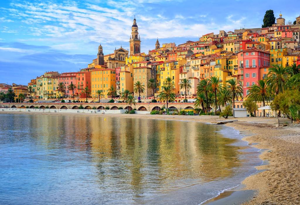 A view of the colorful medieval town of Menton on the French Riviera, France, with colourful houses, the sea and palm trees