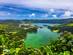 View of twin green-hued crater lakes surrounded by lush hills and vegetation on Sao Miguel island in the Azores