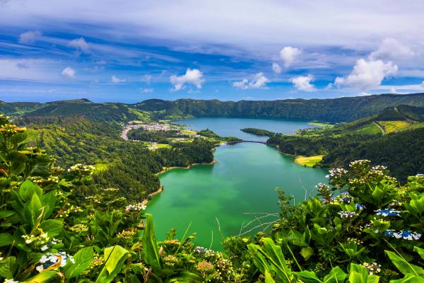 View of twin green-hued crater lakes surrounded by lush hills and vegetation on Sao Miguel island in the Azores