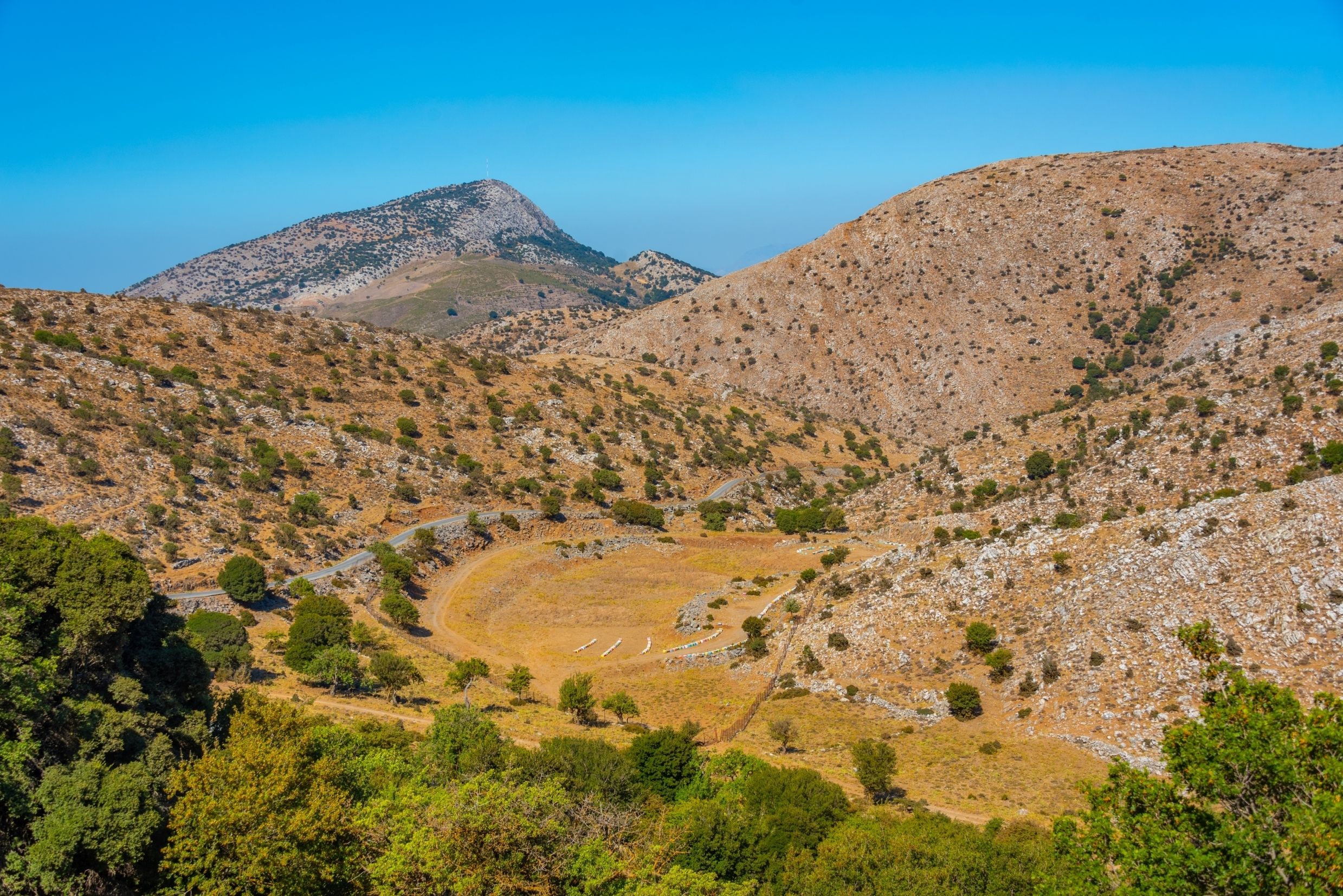 View of rolling sparse mountains with a path winding along them.
