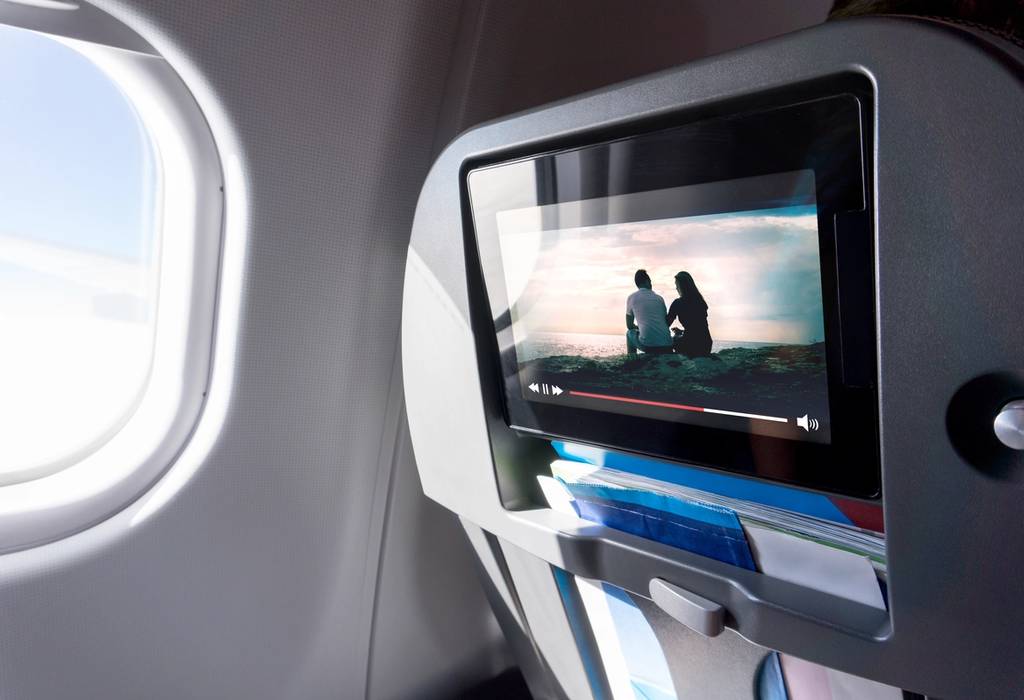 A picture of someone watching a movie on an plane touch screen during a long flight