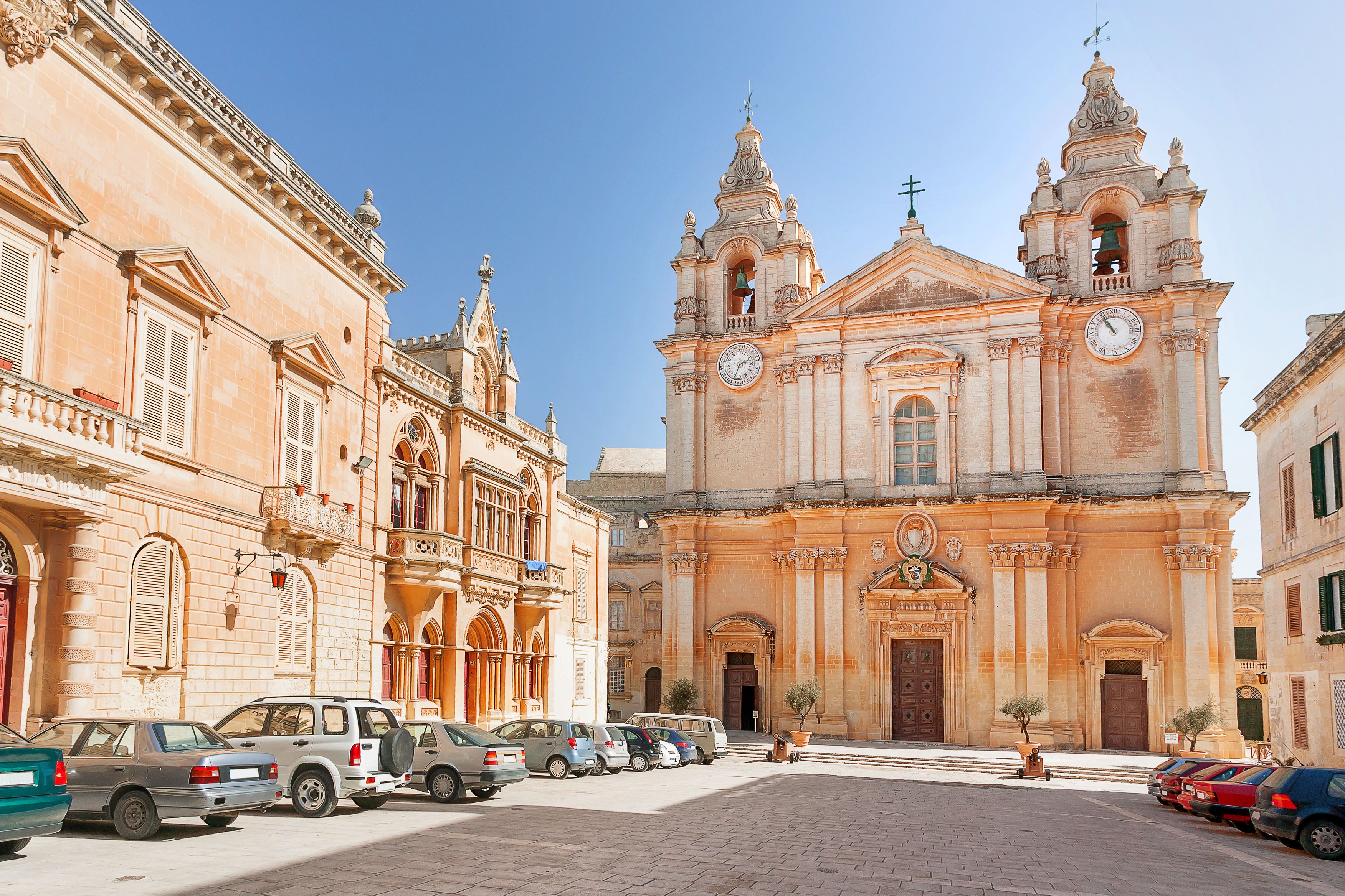 View of a honey-coloured baroque church facing a car-line plaza.