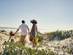 A view of a little girl and her parents walking along a beack with a bucket and spade