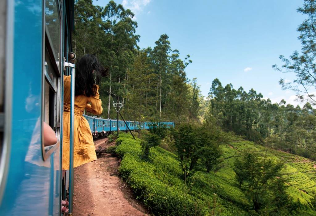 Woman peering out of a train window as it travels through the Sri Lankan tea plantations