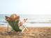 A back view of a woman lounging on a deckchair on a beach looking out to sea