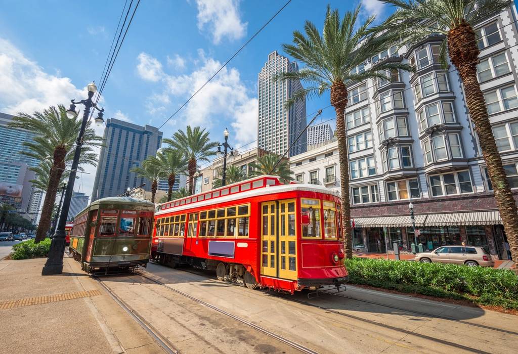 Brightly coloured trams in the city centre of New Orleans in Louisiana with skyscraper buildings on a bright sunny day