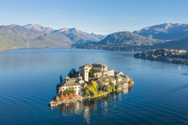A small island adrift in a lake and crowned by the Basilica di San Giulio church