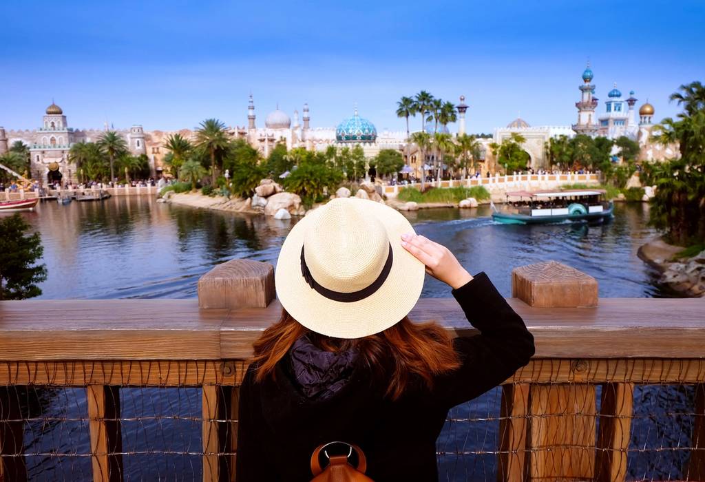 A woman looking out from a bridge at a view of the attractions of Old Town in Disney World, Orlando.