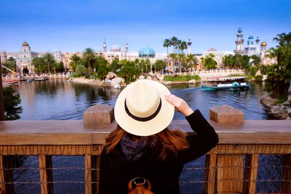 A woman looking out from a bridge at a view of the attractions of Old Town in Disney World, Orlando.