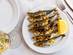 High angle view of a plate of grilled sardines with a lemon on the side.