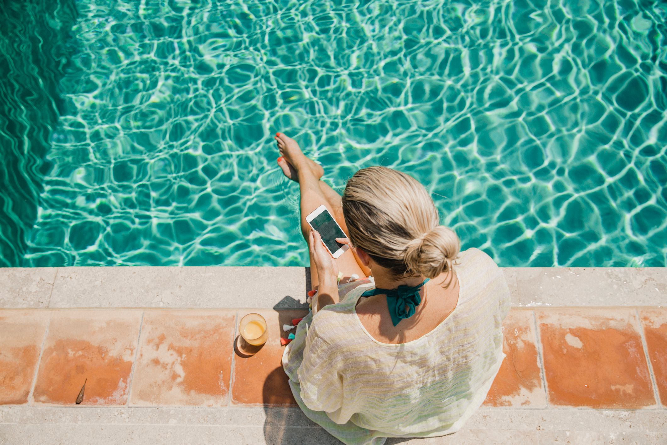 Women sat by the pool on her phone