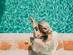 Women sat by the pool on her phone