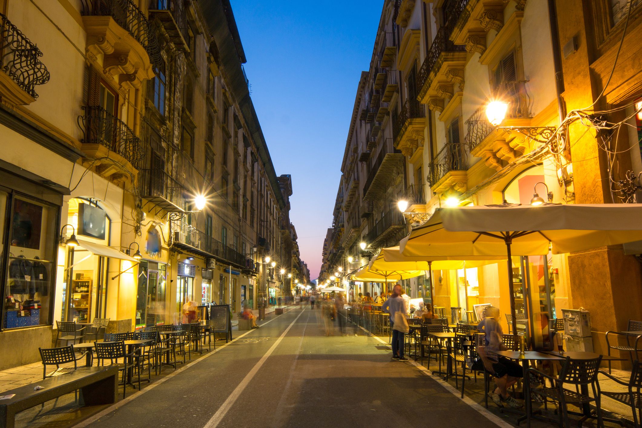 Maqueda Street with outdoor restaurant tables at night time in Palermo, Sicily