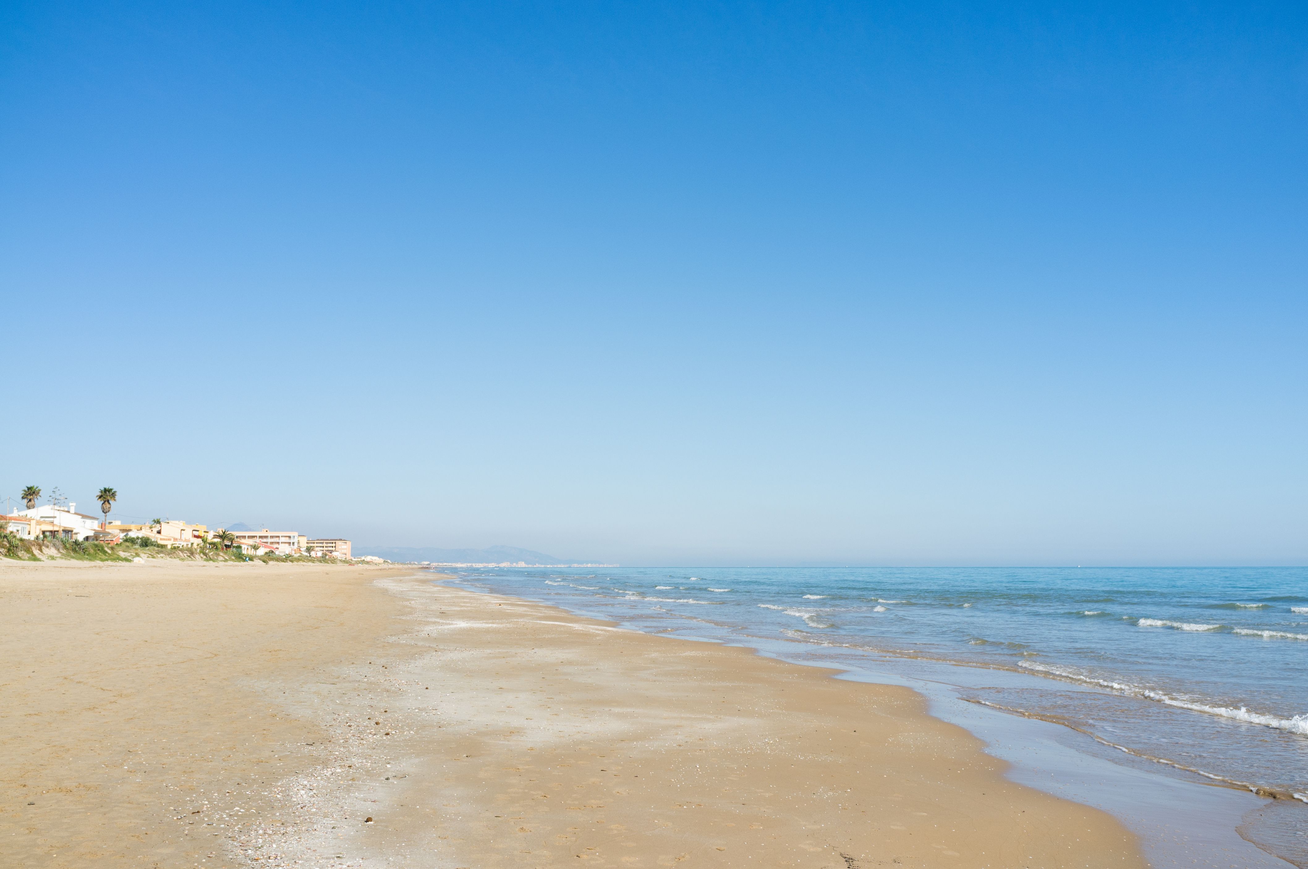 Empty, expansive beach with a town at the far end
