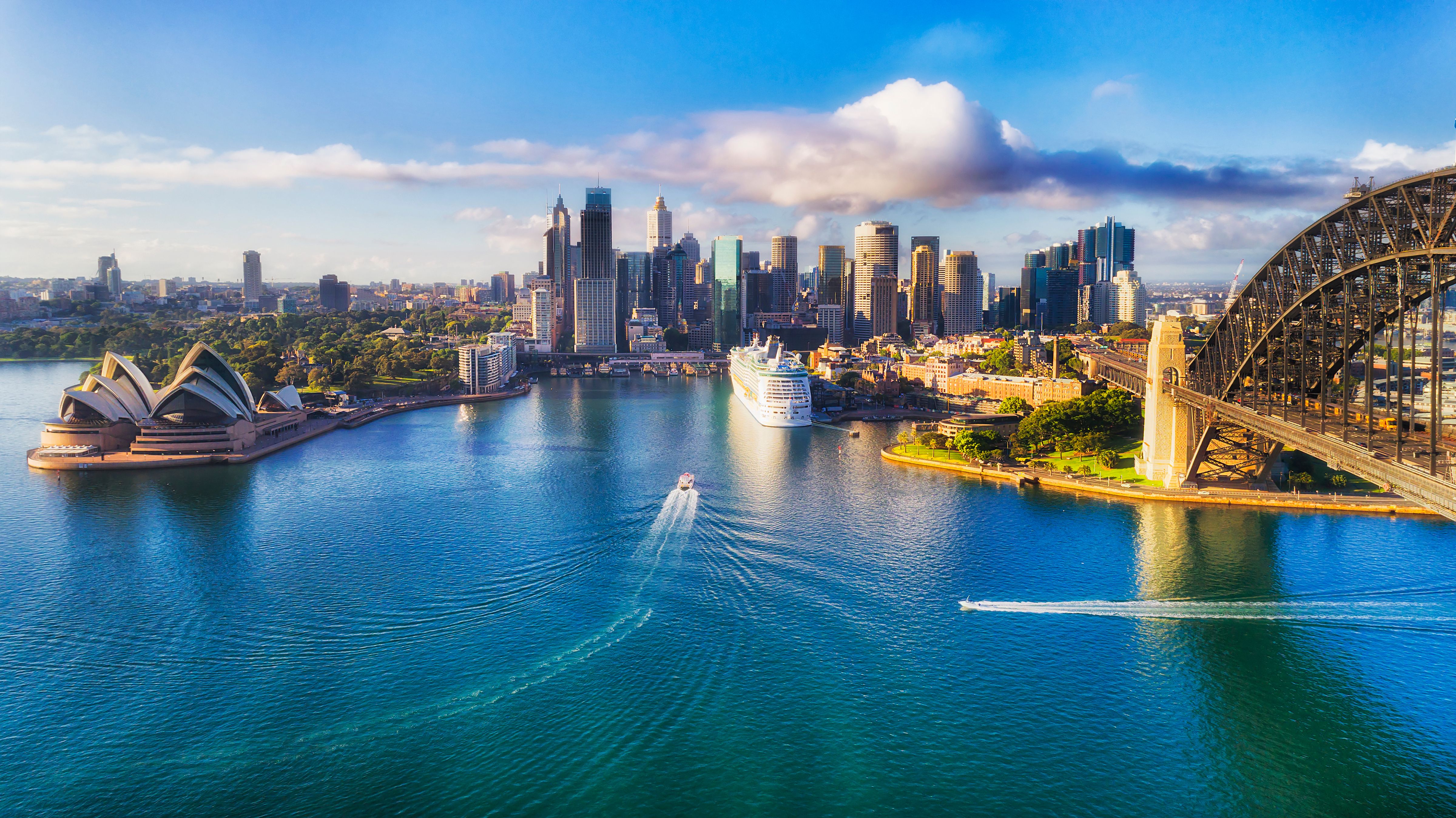 An aerial view of the Sydney Harbour showing the Sydney Opera House and the Sydney Harbour Bridge on a sunny day