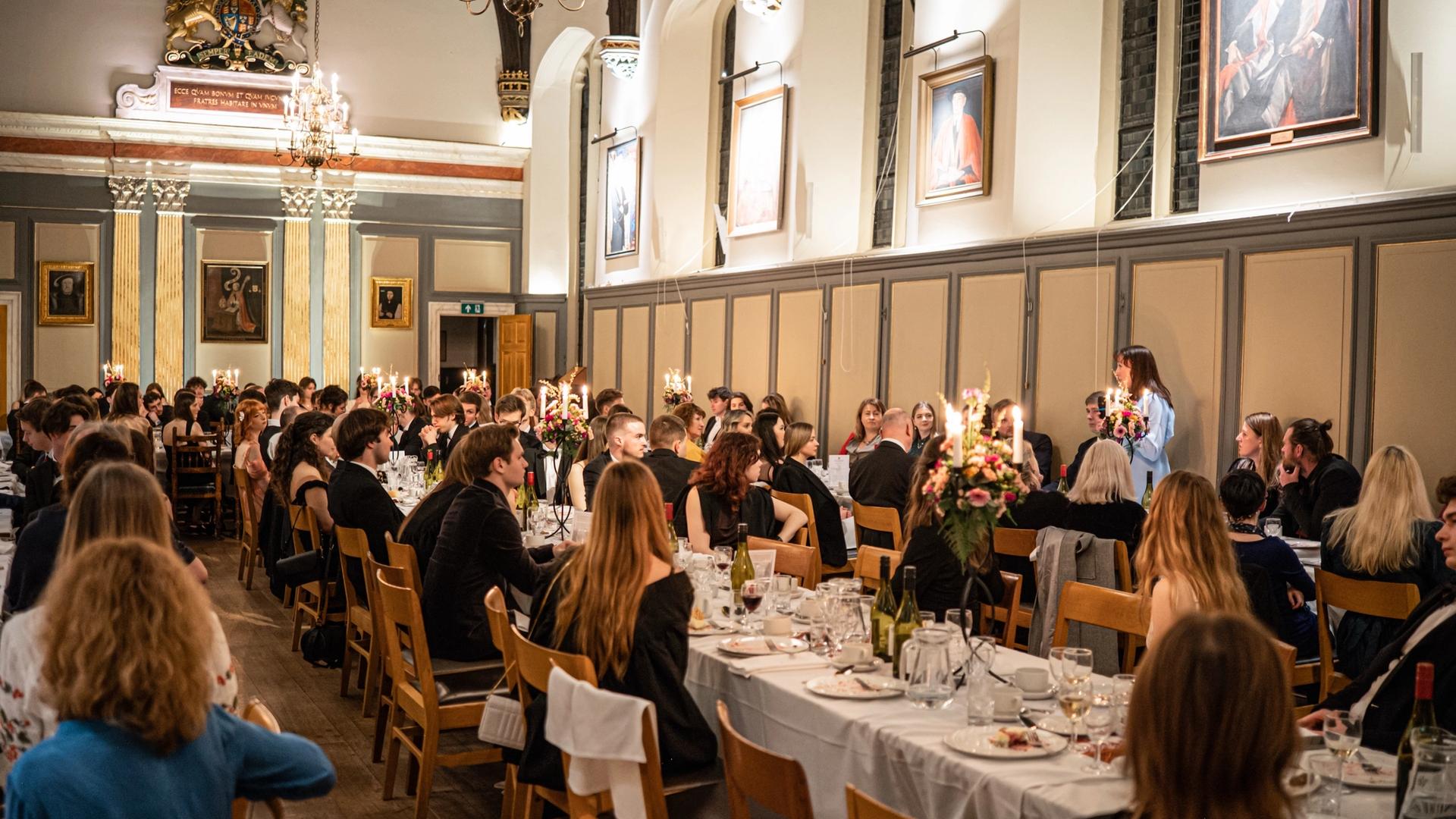 Guests at long candlelit tables in a panelled hall at the CUUS 25th anniversary dinner