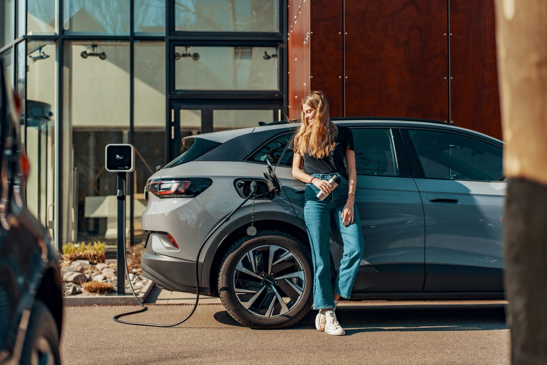 A driver charging an electric car outside a modern building