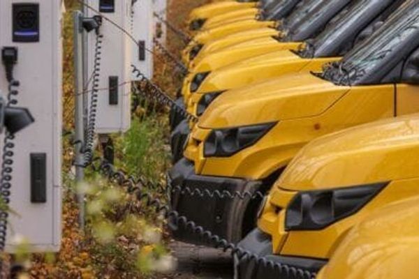 Electric fleet vans charging at a depot, illustrating how EV charging can generate revenue through carbon credits