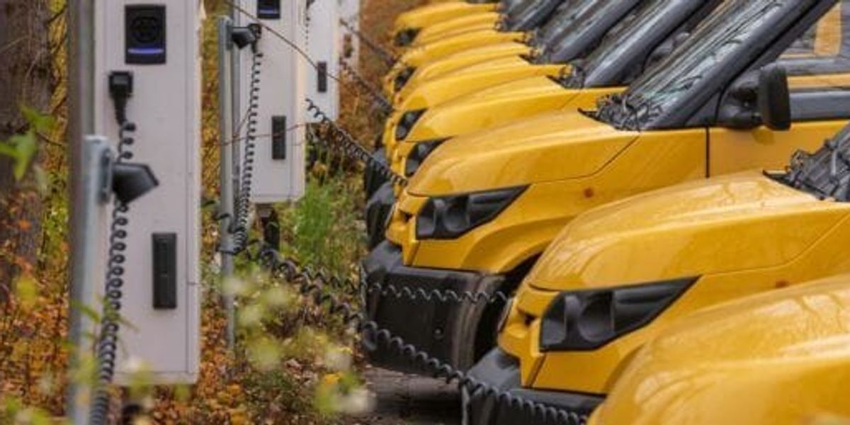 Camionnettes de flotte électrique en charge dans un dépôt, illustrant comment la recharge de VÉ peut générer des revenus grâce aux crédits de carbone