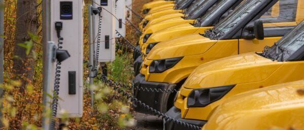 Electric fleet vans charging at a depot, illustrating how EV charging can generate revenue through carbon credits