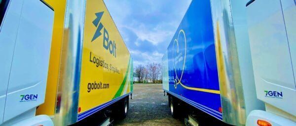 Side-by-side comparison of leased and owned electric delivery vans in a fleet depot with charging stations