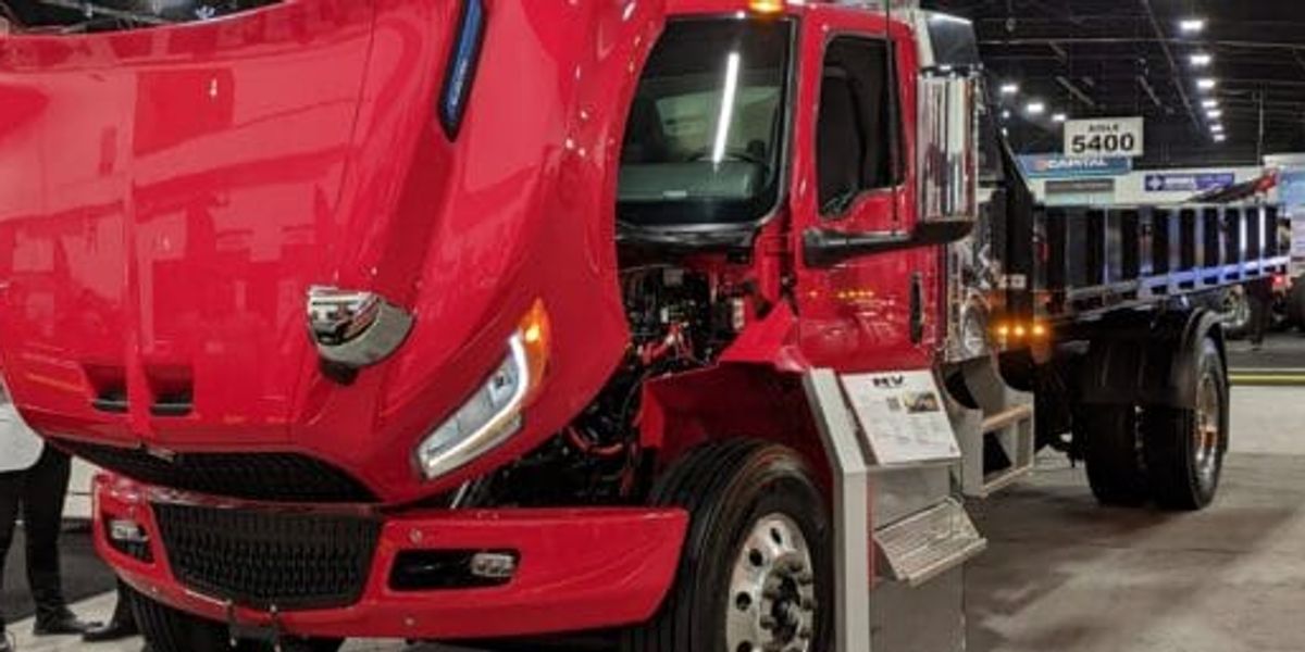 Electric commercial trucks charging at a depot, illustrating modern EV battery technology for fleets