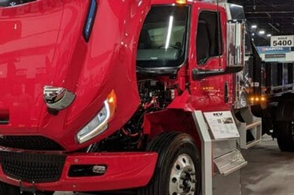 Electric commercial trucks charging at a depot, illustrating modern EV battery technology for fleets