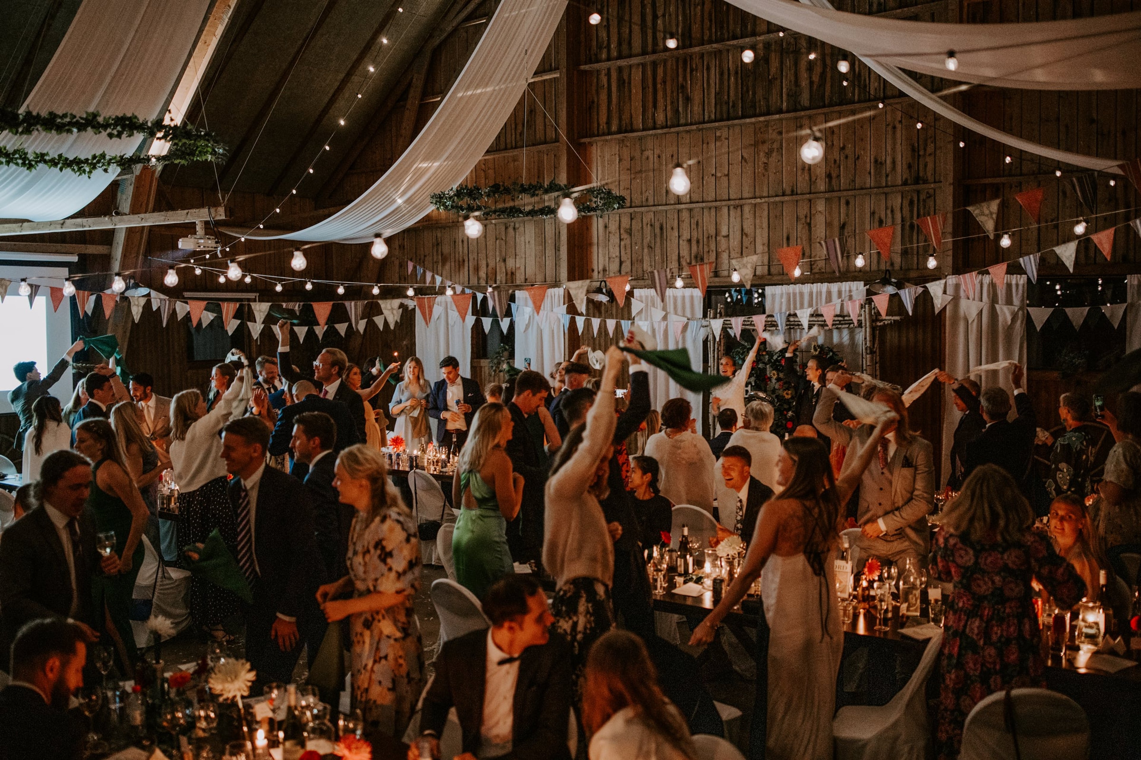 Fullsatt bröllopsfest i Logen under vimplar, kransar och ljusslingor