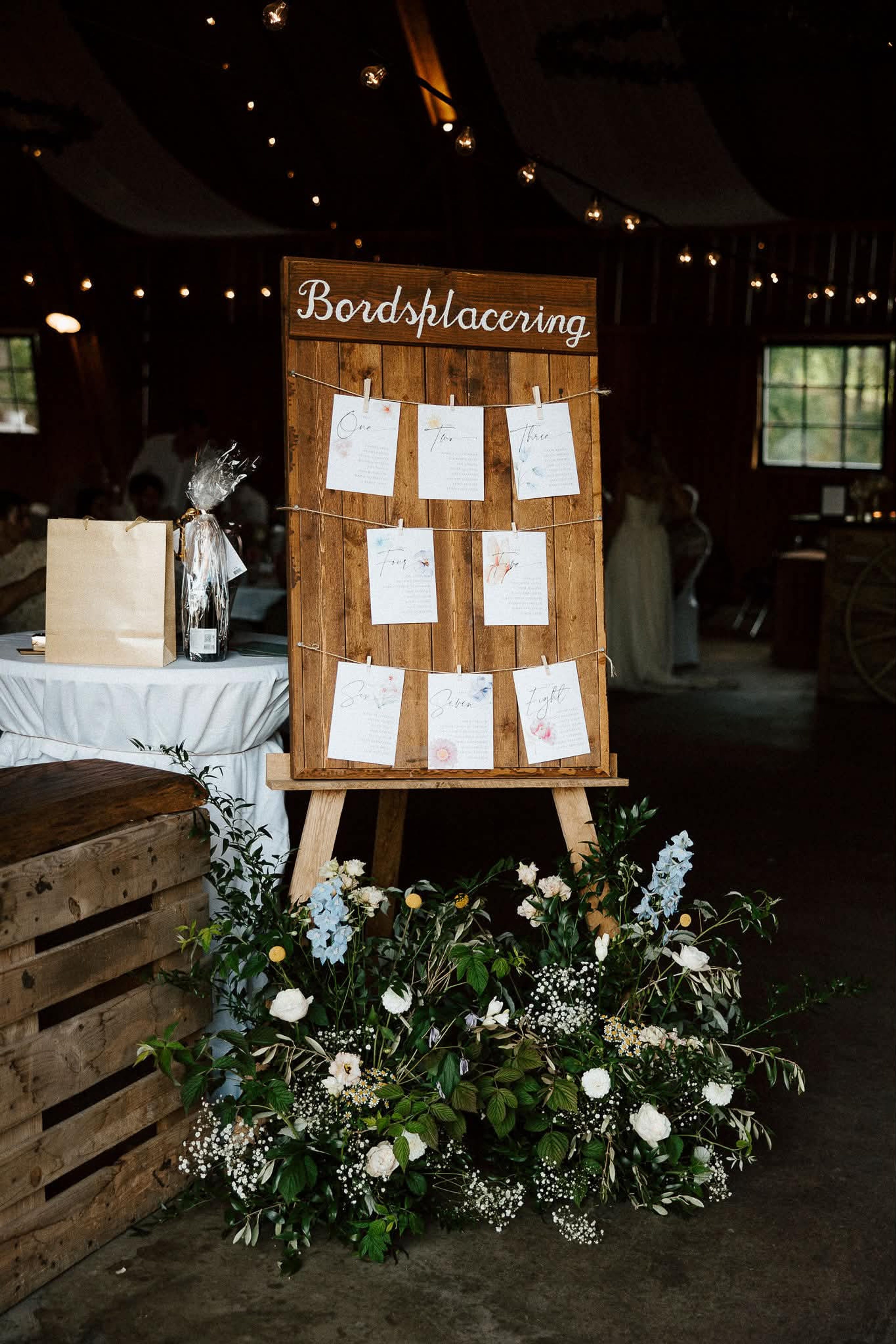 Bordsplaceringen på ett rustikt staffli med blomsterarrangemang och bröllopstårta