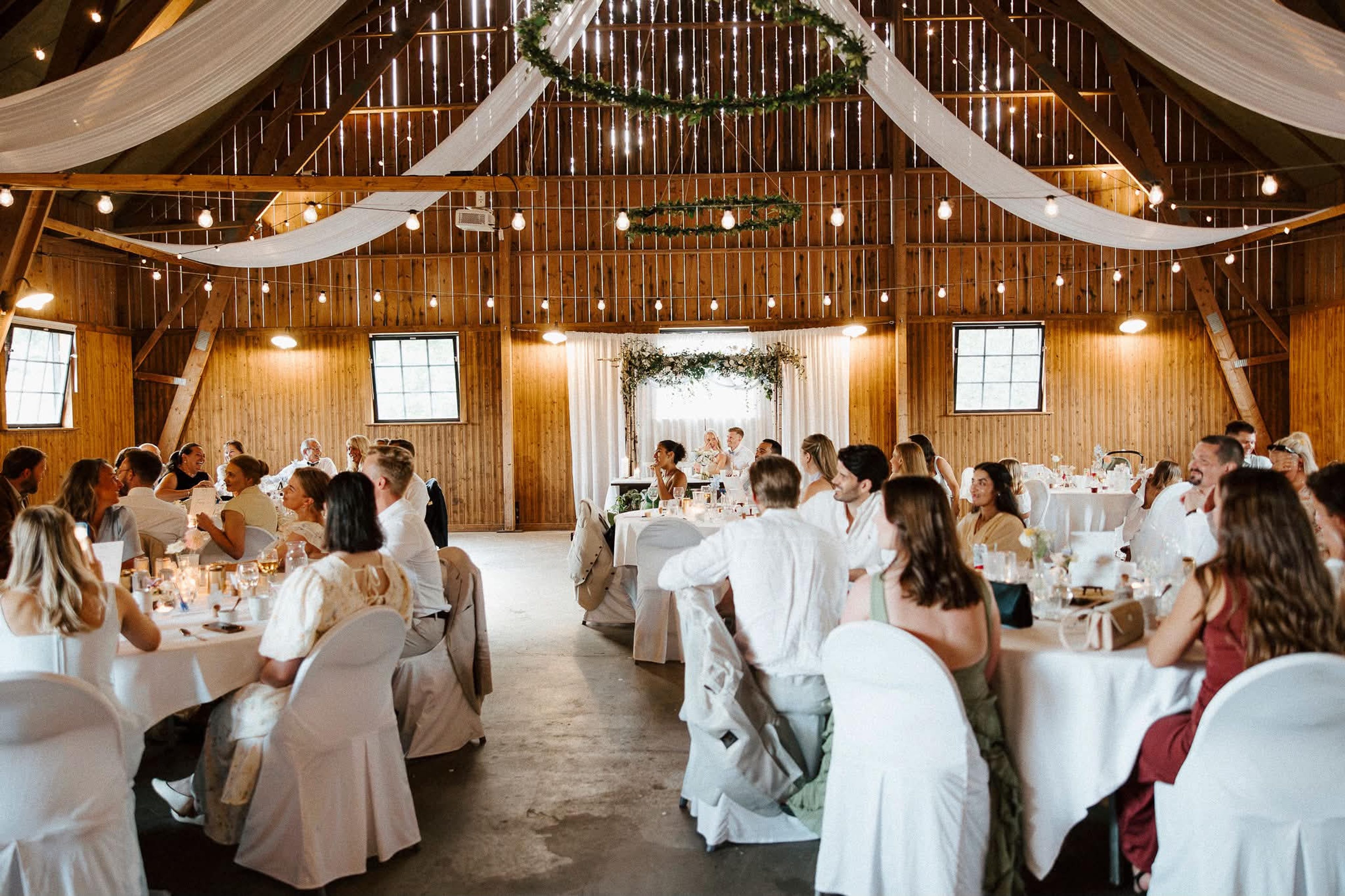Gäster vid dukade bord under draperier och ljusslingor i logen