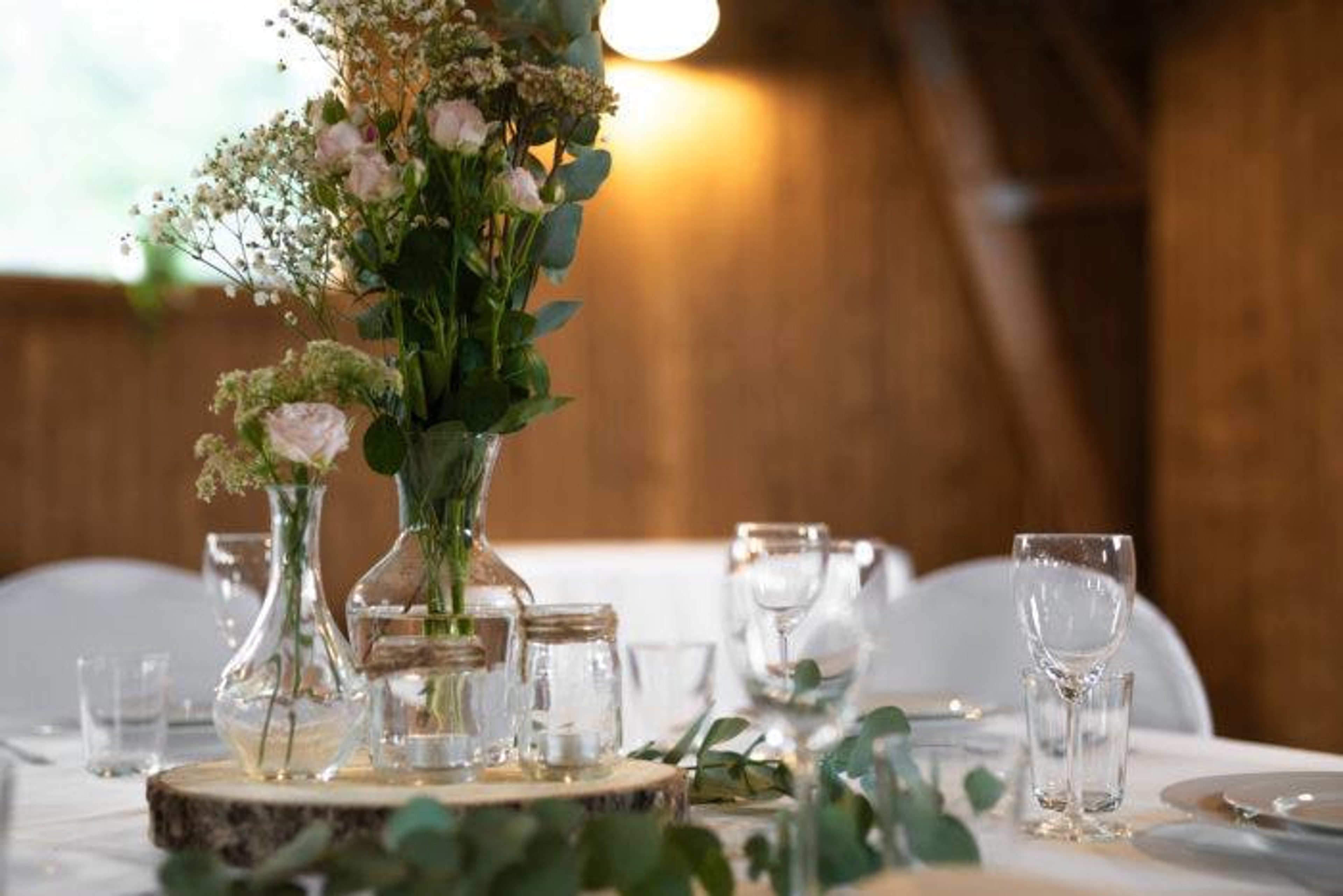 Blomsterarrangemang med rosor och eukalyptus mitt på ett dukat bord