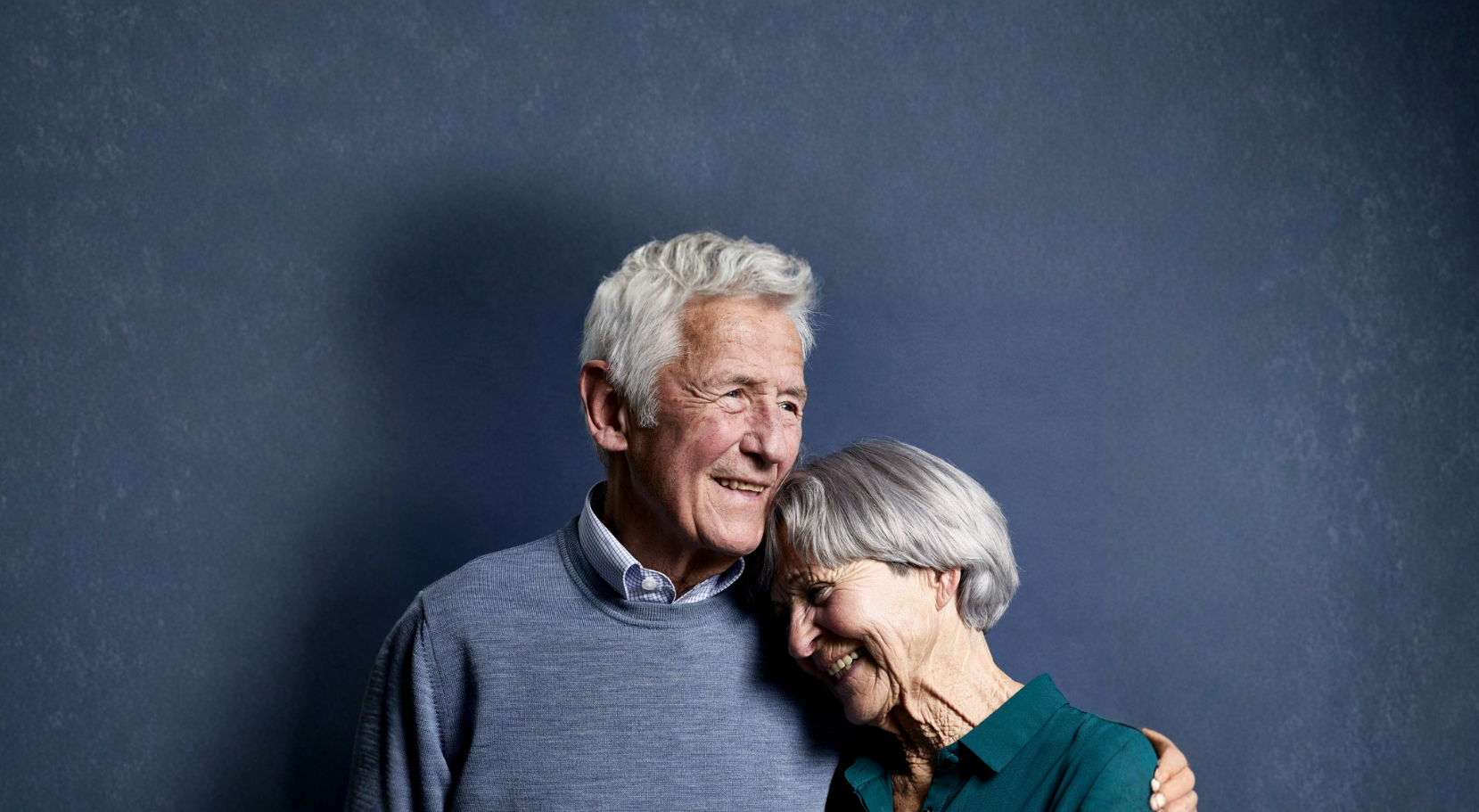 Older man with arm around a woman smiling - moving from retirement village villa into aged care