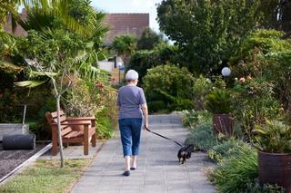 Resident walking her dog through the village grounds at Highlands