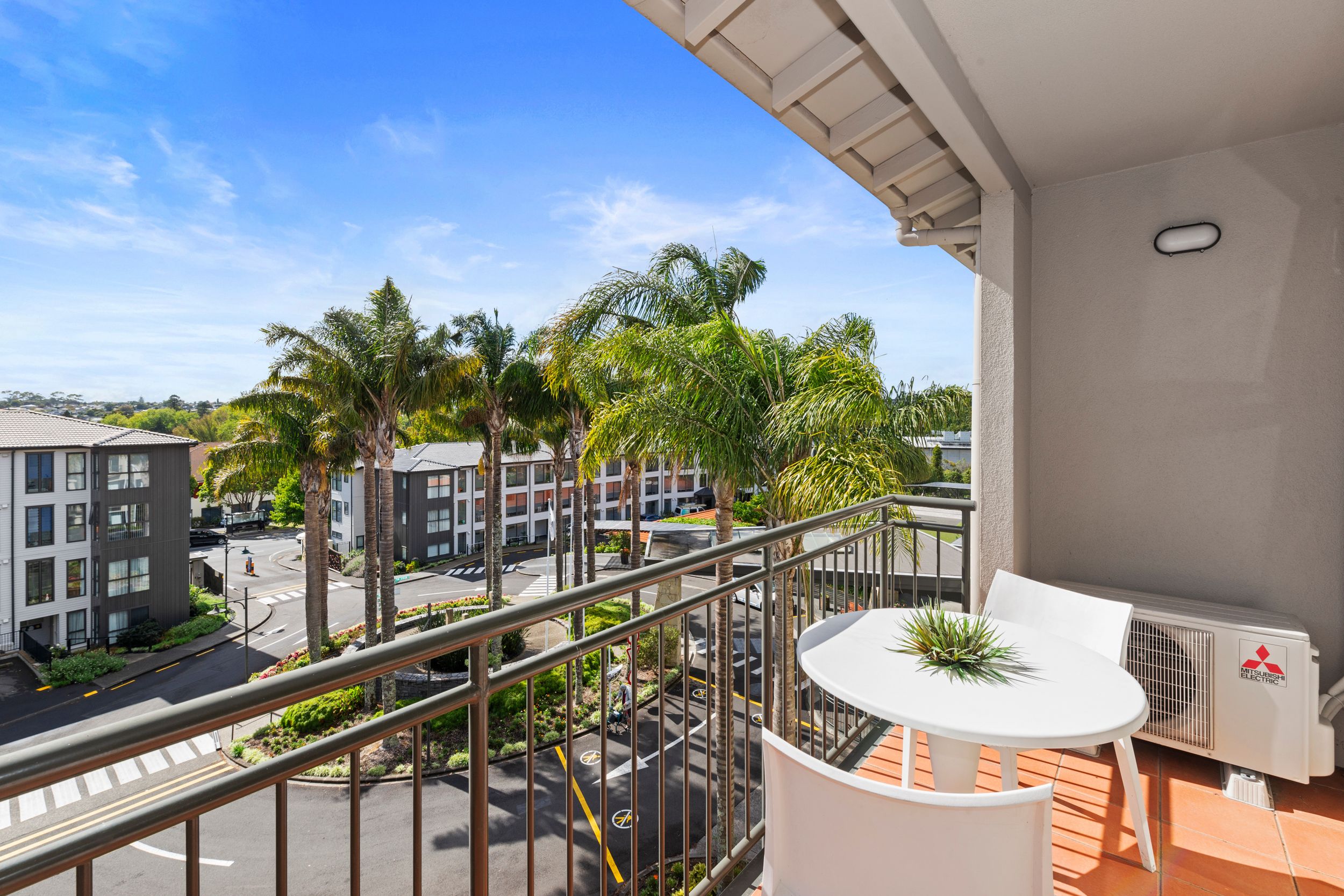 WTG from apartment building with deck and balcony with chairs and palms in the background