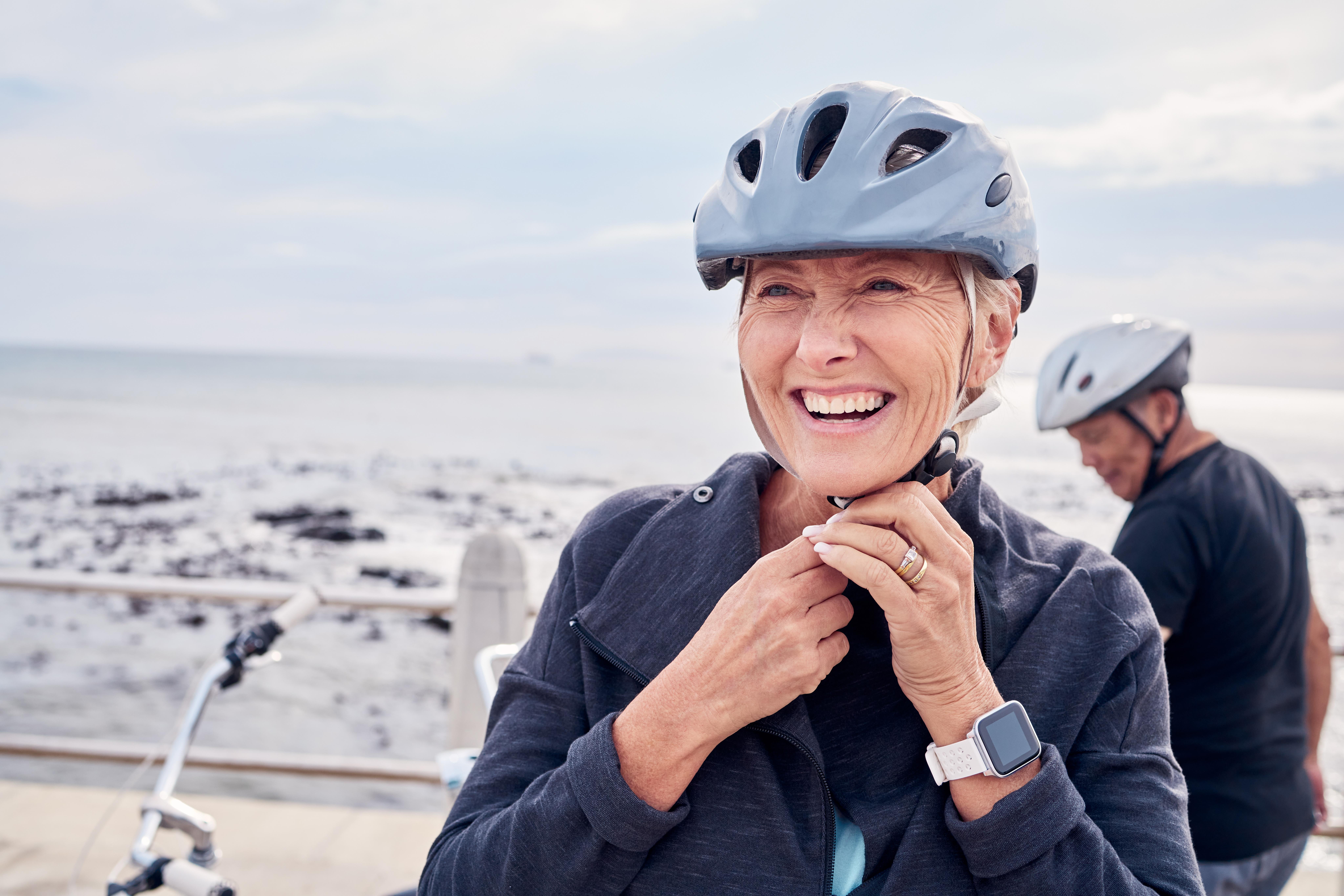 Lady riding bike along beachside smiling