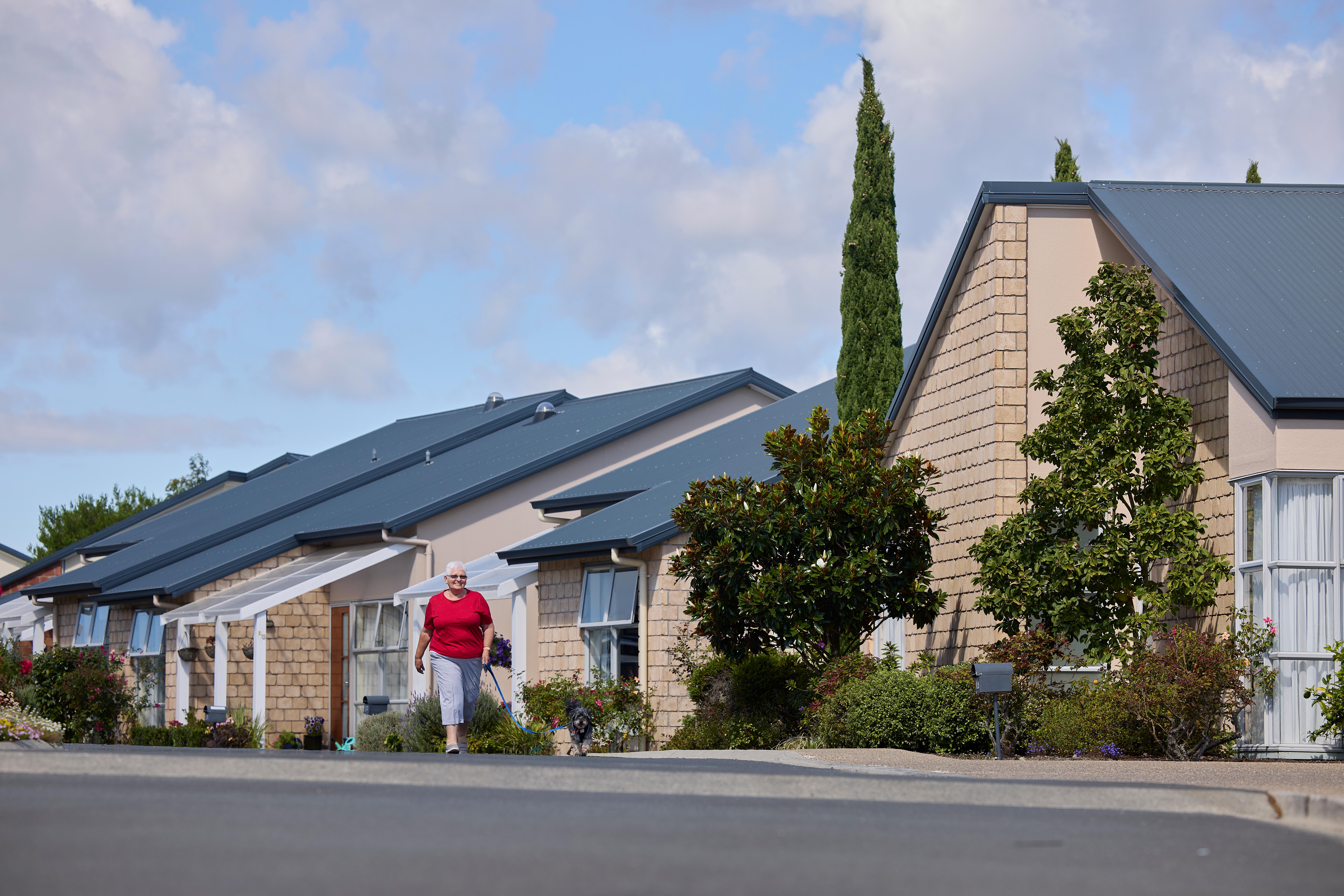 Resident walking her dog at Forest Lake Gardens with townhouses behind
