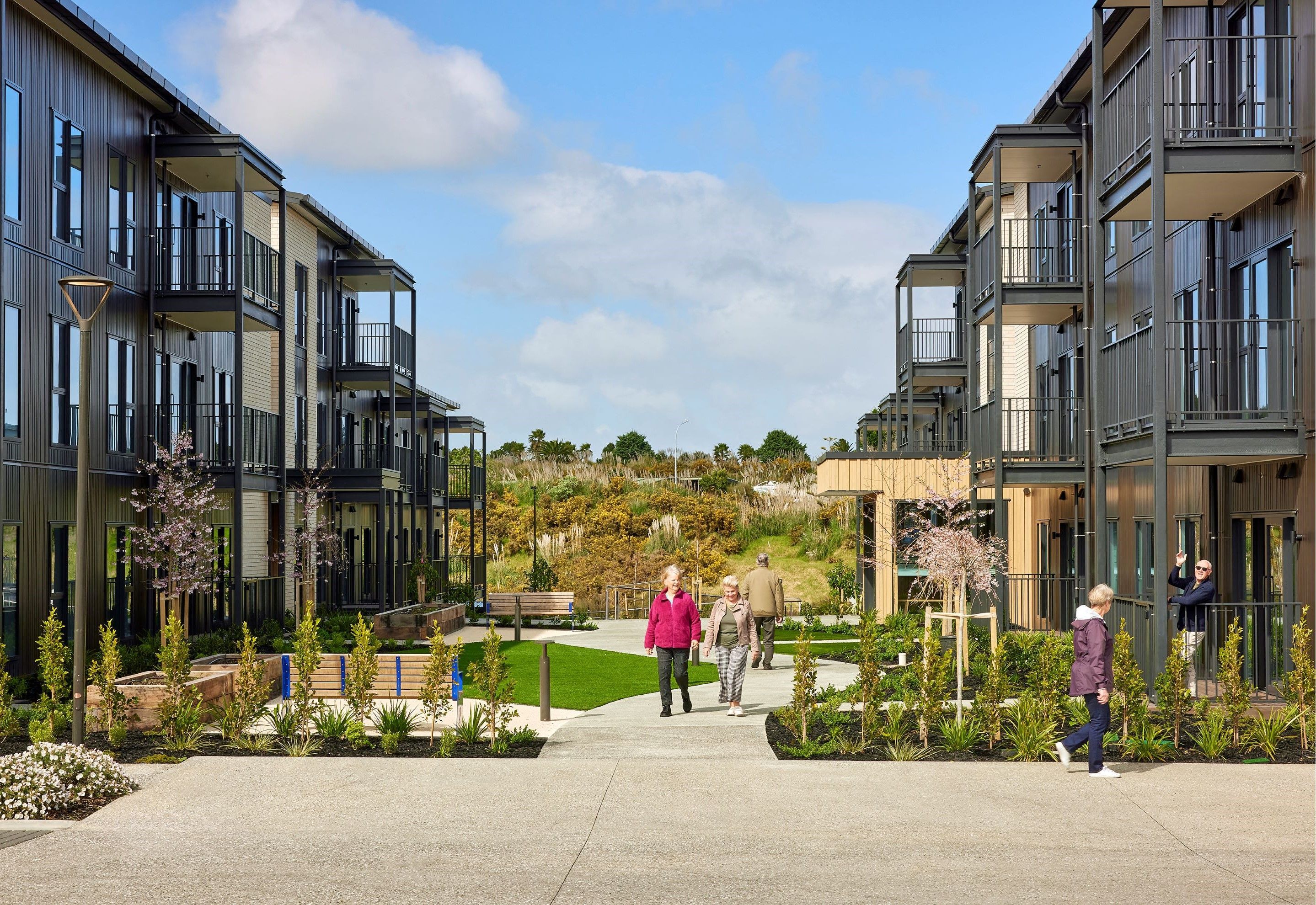 Residents walking through the village grounds at Pohutukawa Landing