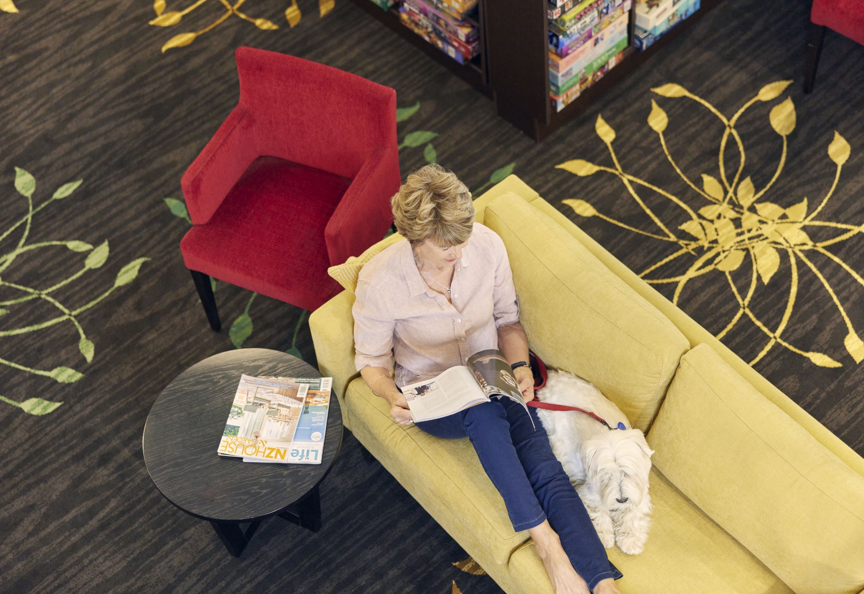 Resident reading a book in the library at Greenwich Gardens