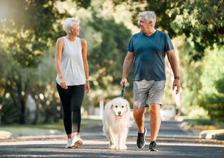 Smiling couple walking their dog outdoors