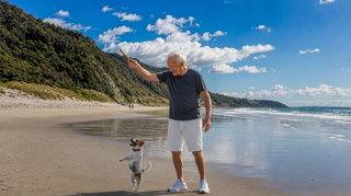 Elderly man with dog plays on the beach