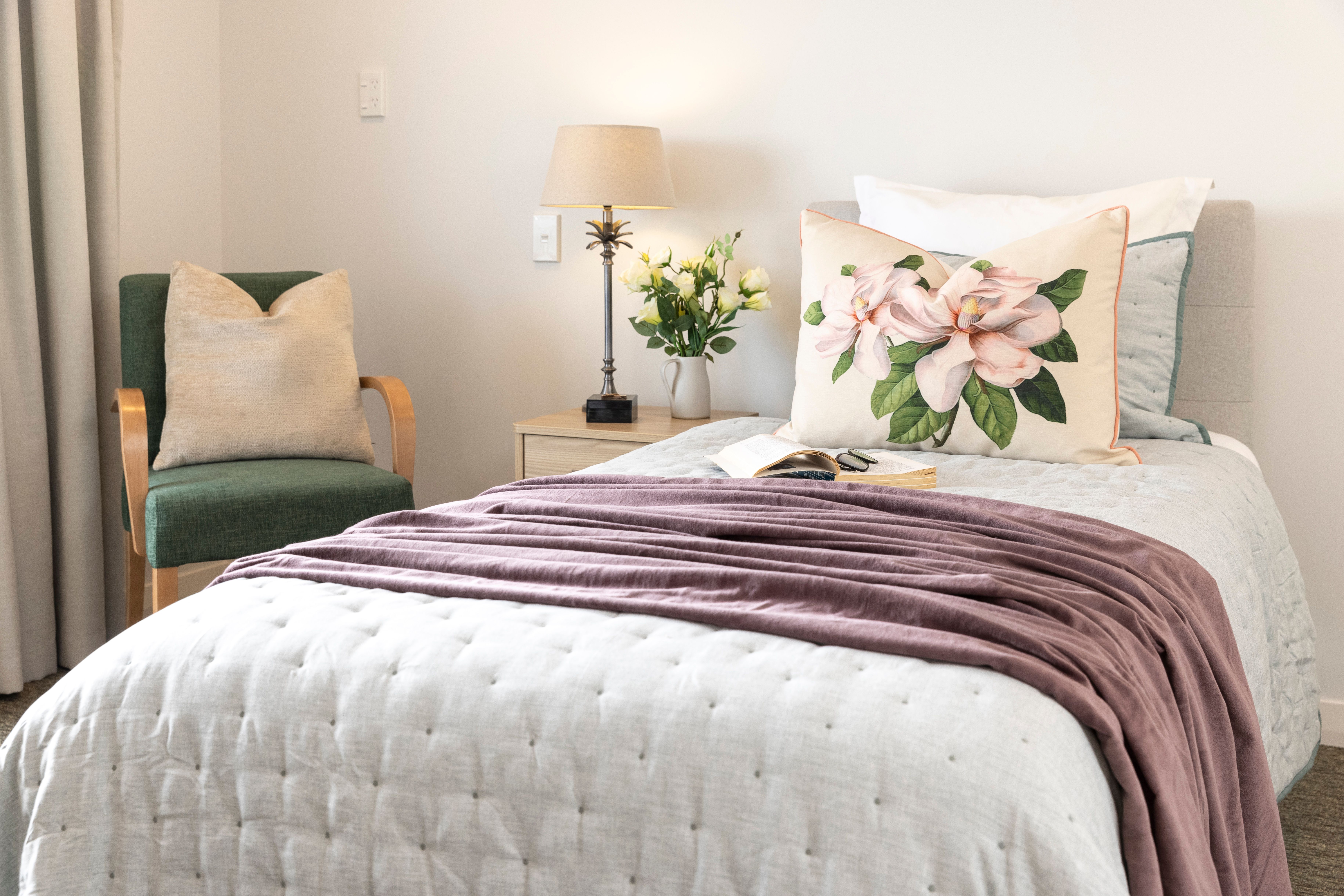 Picture of a bed in a care room with lovely bedspread and cushions