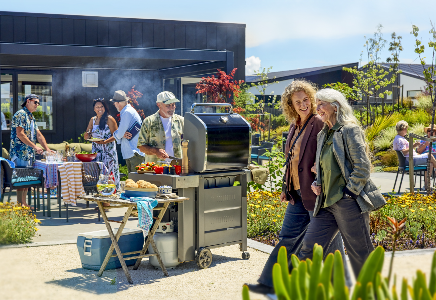 Residents enjoy a BBQ while visitors tour Pohutukawa Gardens village