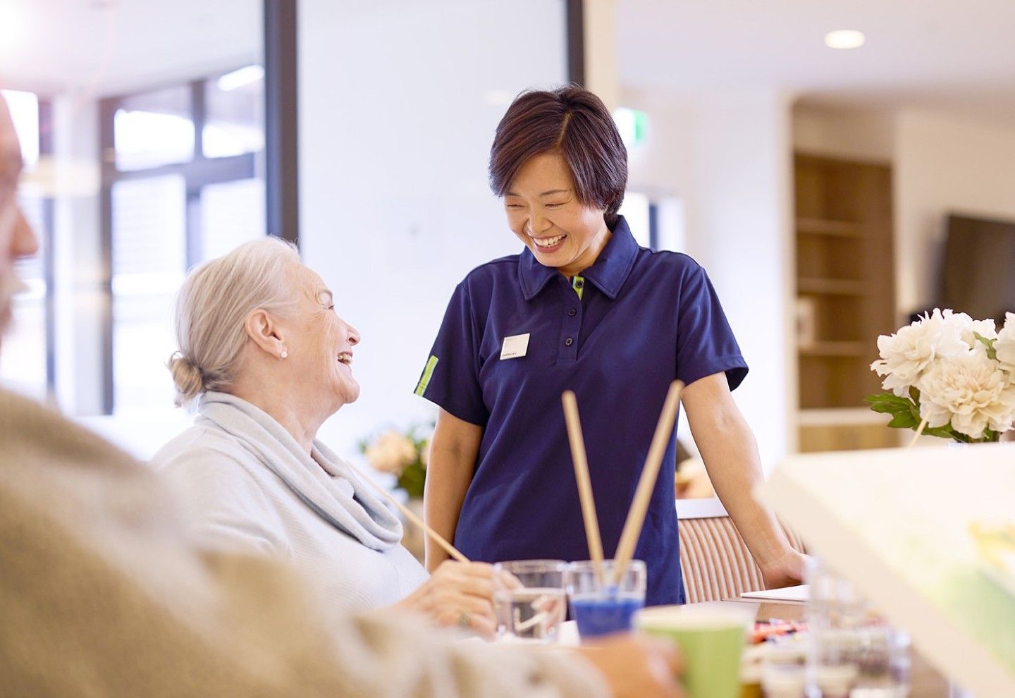 village resident painting and smiling at aged care nurse