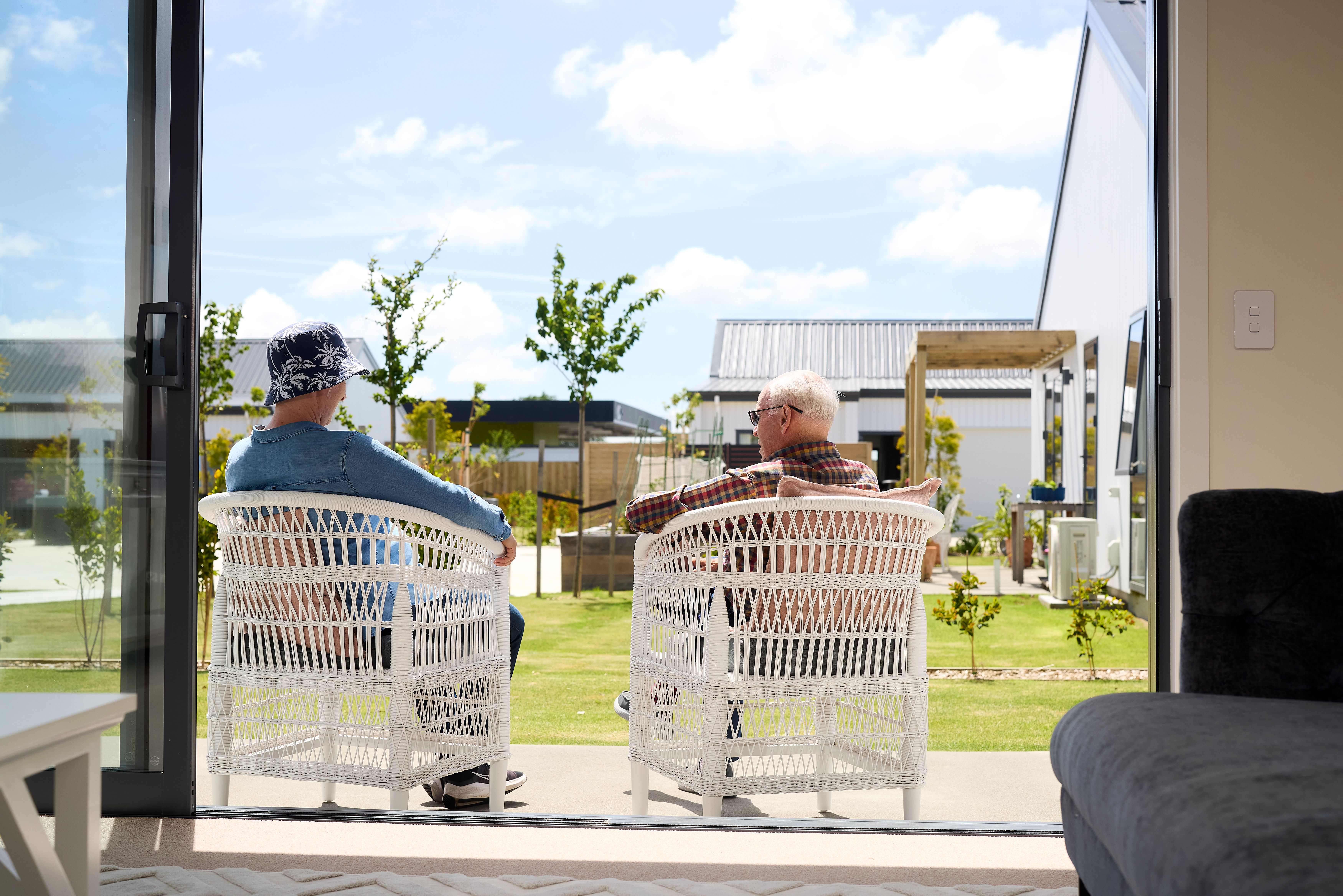 Two friends sitting on patio chatting in the sun