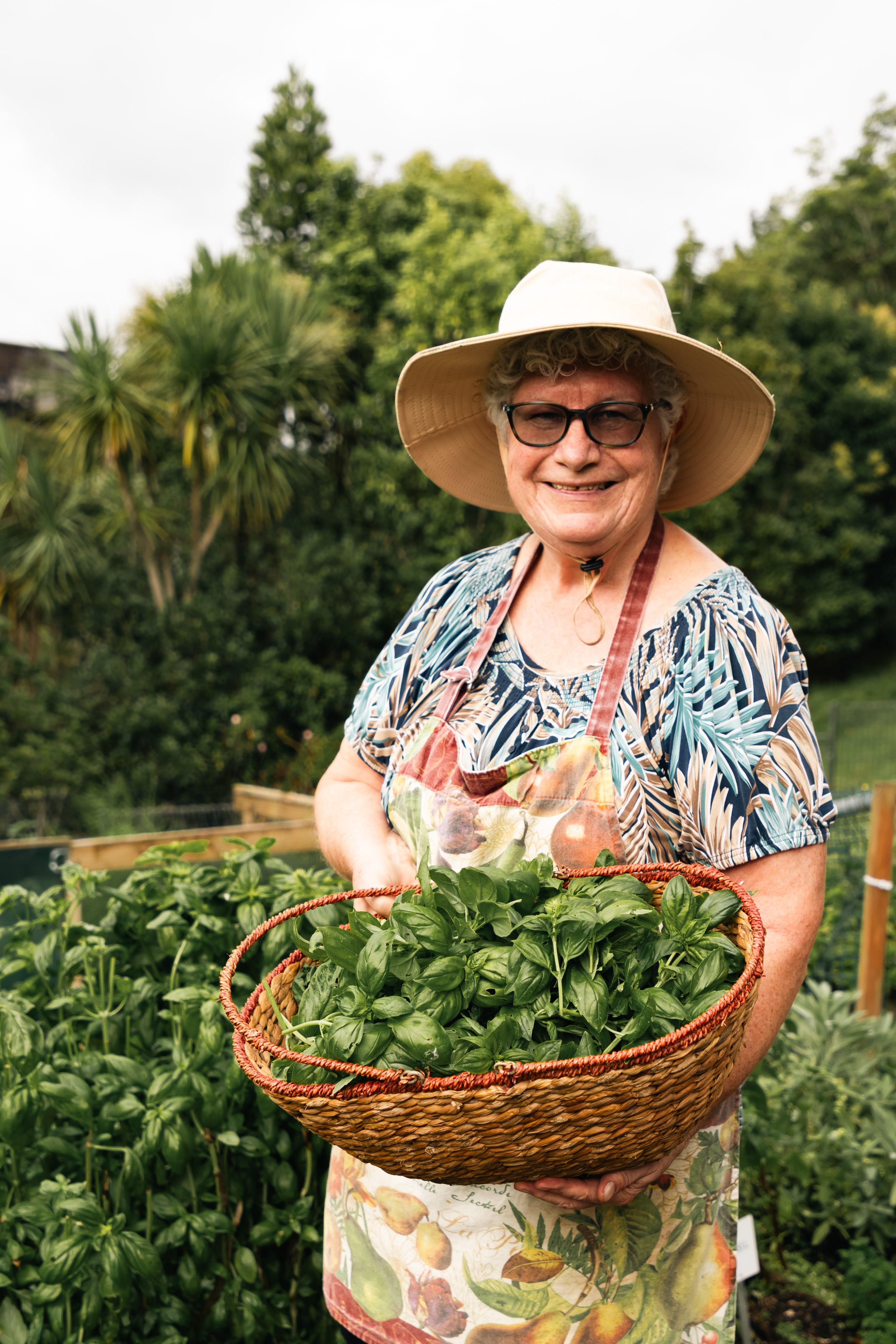 Residents smiling with basil and plants and veges behind her