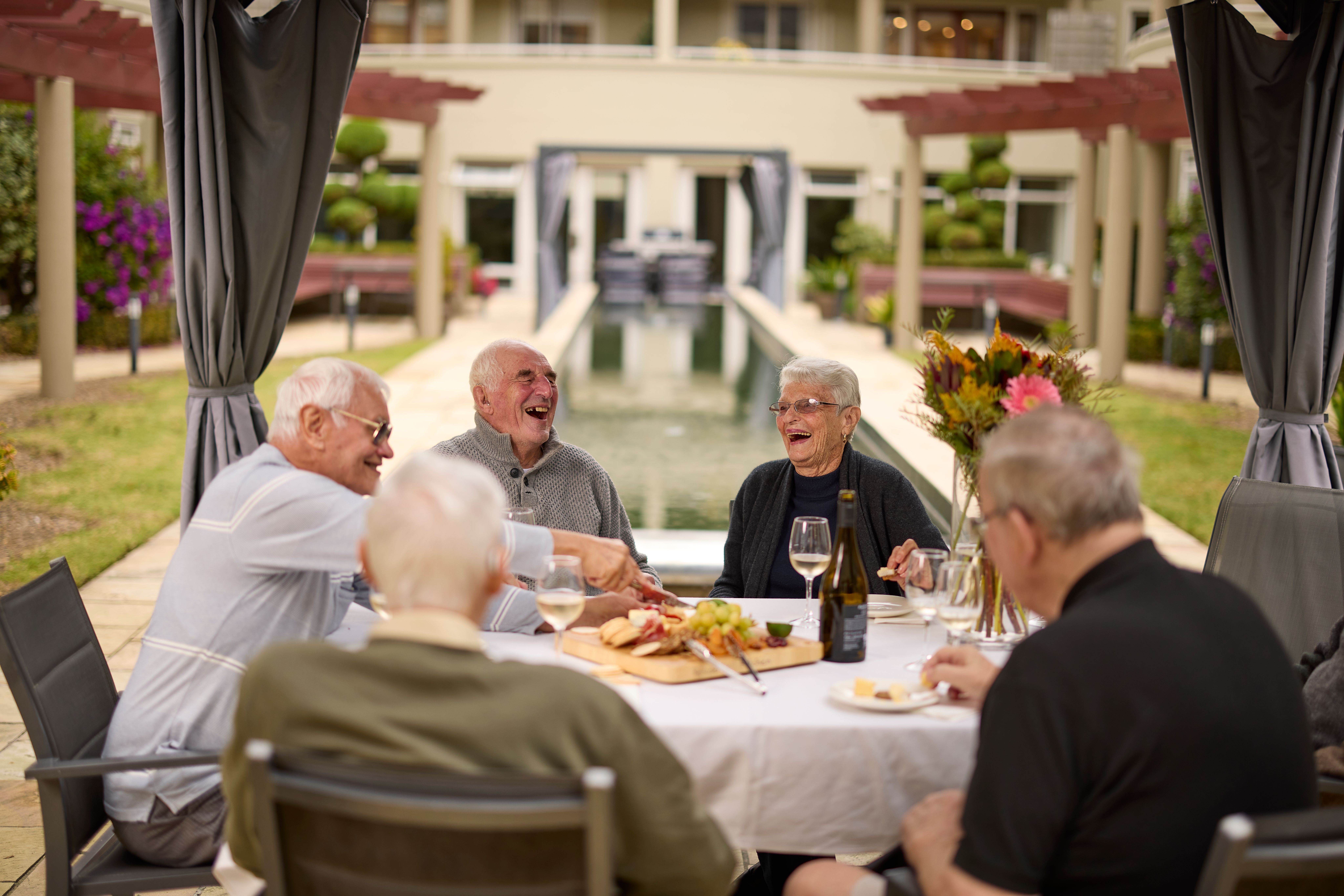 Residents smiling in courtyard eating and drinking 