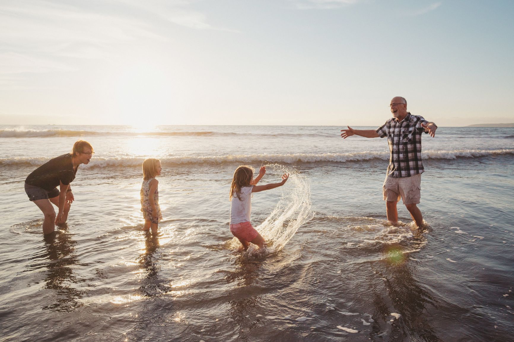 Family playing on a beach as elderly gentlemen embraces retirement