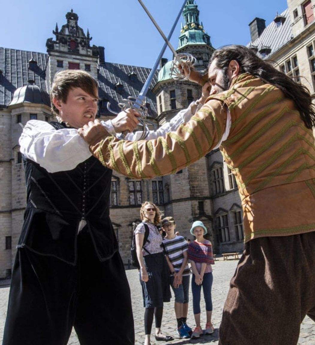 Skuespillere der kæmper med sværd i gården