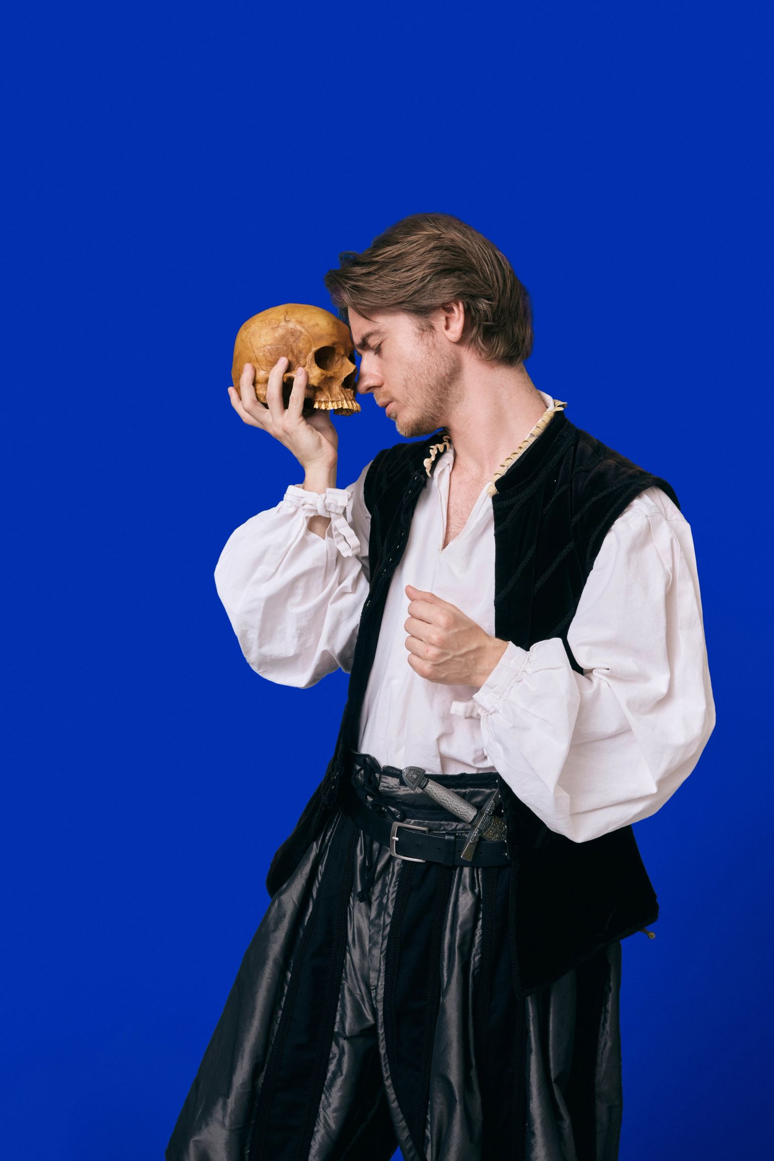 Ung mand i renæssancekostume holder en kranik op til sit ansigt – inspireret af Hamlets 'Alas, poor Yorick'-scene, reklamefoto til Hamlet-oplevelser på Kronborg