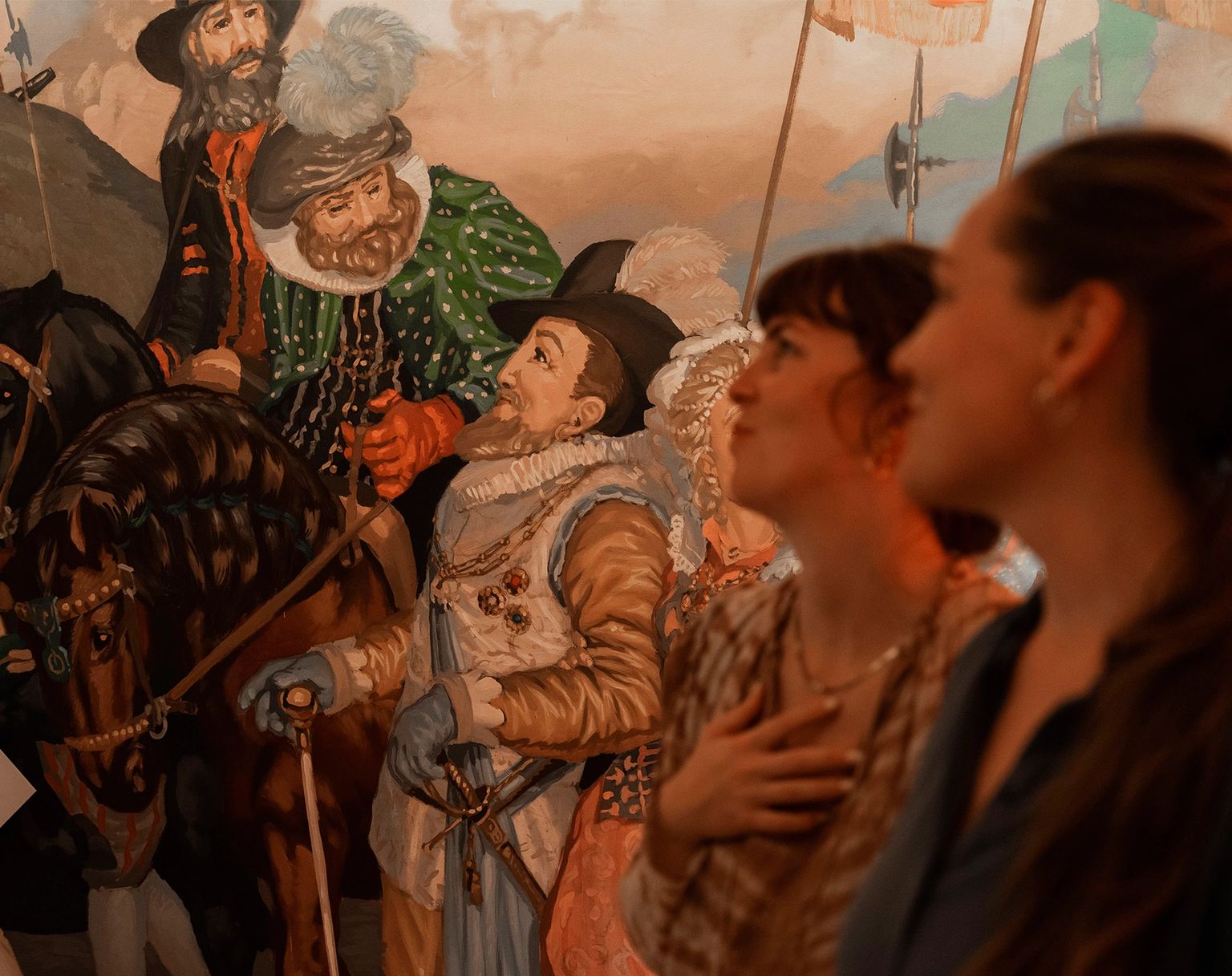Two women looking at a historical painting in a museum.